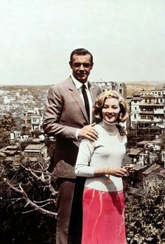 a man and woman standing next to each other in front of a cityscape