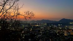 the sun is setting over a cityscape with mountains in the backgroud