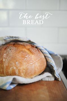 a loaf of bread sitting on top of a wooden table next to a blue and white towel