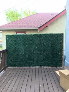 a box sitting on top of a wooden deck next to a green privacy fence with boxes