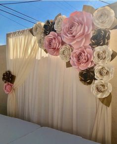 the backdrop is decorated with paper flowers and ribbon tied to it's sides for an elegant touch