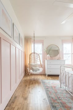 a bedroom with pink walls and wooden floors, white furniture and hanging hammock chair