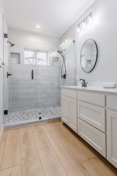 a bathroom with wood floors and white walls, along with a walk - in shower