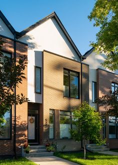 two story brick house with grass and trees in front