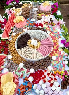 a table topped with lots of candy and candies next to watermelon slices