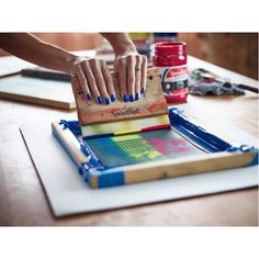 the woman is using her hands to make art work on paper and paintbrushes