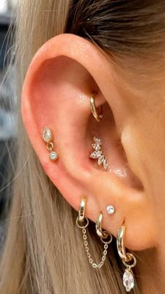 a woman wearing three different types of ear piercings