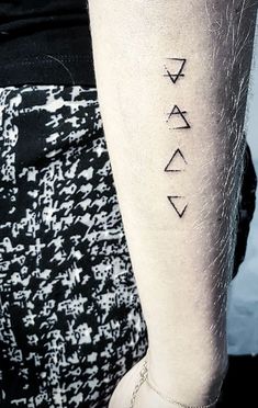 a woman's arm with three different symbols tattooed on the left side of her leg