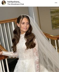 a woman wearing a wedding dress and veil standing on stairs with her hand in the air