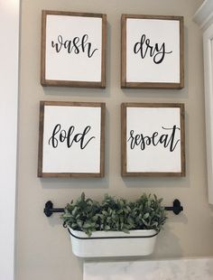 three wooden signs hanging on the wall above a planter with greenery in it