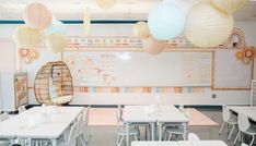 a classroom with tables, chairs and paper lanterns