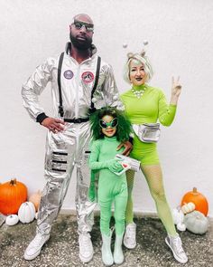 a man and two women in costumes standing next to each other with pumpkins behind them