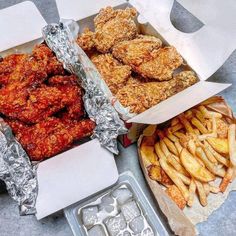 chicken wings and fries in tin foil next to an ice tray with muffins