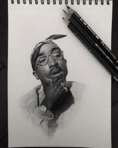 a pencil drawing of a man with glasses and a feather on his head, next to two crayons