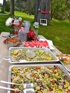 an outdoor buffet table with food and utensils