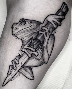 a frog with a knife in its mouth tattoo on the leg, done by person