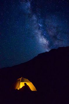 a tent is lit up at night with the milky in the background