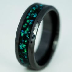 a black ring with green and blue opal inlays on the inside of it