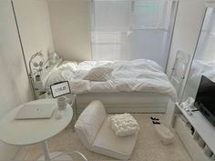 a white bedroom with a bed, desk and television