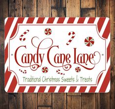 a candy cane lane sign on a wooden wall with red and white striped border around it