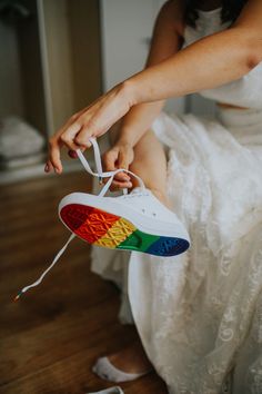 a woman is tying her shoelaces with white lace and rainbow colors on it