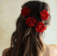 a woman with long hair and red roses in her hair is shown from the back