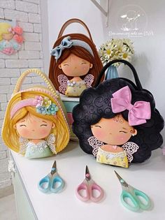 three little dolls sitting on top of a table next to some scissors and other items