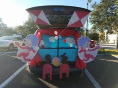 the back end of a vehicle decorated with paper cutouts and balloons, in a parking lot