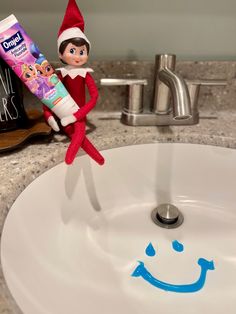 an elf is sitting on the edge of a sink with toothpaste in front of it