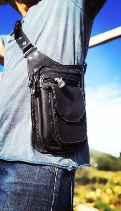 "Black Leather waist bag with leg holster This Holster Bag Pack with a minimalist design is the safest and most functional bag ever created. Our simple strap system changes the look and function of the bag different stylish ways: Thigh Holster, Shoulder Holster and Fanny Pack. Incorporates 3 separate pockets, can hold a variety of items with its one large main zippered compartment, a second zippered pocket, and a secret inside zippered pocket . Use me the way you like it! Great for holding your Black Belt Bag With Cell Phone Pocket For Everyday, Multifunctional Black Chest Bag For Everyday Carry, Black Belt Bag With Multiple Pockets For Travel, Black Travel Belt Bag With Multiple Pockets, Functional Black Belt Bag With Multiple Pockets, Functional Leather Belt Bag With Anti-theft Pocket, Functional Leather Shoulder Bag With Anti-theft Features, Functional Leather Anti-theft Shoulder Bag, Functional Leather Belt Bag For Outdoor Activities