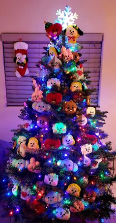 a christmas tree with many stuffed animals on it's top and lights in the bottom