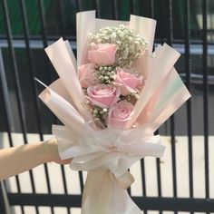 a person holding a bouquet of pink roses and baby's breath in their hand