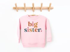 Big Sister Sweatshirt, Big Sister Announcement, Pregnancy Announcement, Big Sister Shirt, Baby Announcement, Pregnancy Reveal Shirt, Big Sis 💗  Welcome to The WildflowerbyMiley Etsy Shop!  This listing is for the bodysuit, sweatshirt or t-shirt only. All other items that are shown in our photos such as shoes, hats, beanies, blankets etc. are for photo staging purposes and are NOT INCLUDED in the sale. DESCRIPTION:  This baby and children's unisex essential fits like a well-loved favorite. Super soft t-shirts, sweatshirts and baby bodysuits for your little lads and gals meant to showcase their big personalities. Its Excellent quality and vibrant print makes one fall in love with it over and over again.  This adorable piece is the perfect lightweight layer for casual wearing.  This product Pregnancy Announcement Big Sister, Sister Announcement, Big Sister Announcement, Pregnancy Reveal Shirt, Announcement Pregnancy, Kids Jumpers, Big Sister Shirt, Soft Cute, Pregnancy Reveal