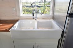 a white kitchen sink sitting under a window