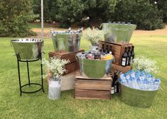 several metal buckets filled with water and bottles on top of grass next to trees