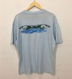 "*ITEM: Vintage 90s Oneill Surfwear Large Vintage 1990s Oneill Surfing TopTees Tshirt Size L *ITEM DETAILS: 👇🏻 Please be aware that all vintage items will usually show a few signs of wear or fading due to age, but anything visible such as stains or holes, and serious flaws have been photographed.For any further information on this item please contact us and we will be happy to help. *SIZE:LARGE *ACTUAL SIZE MEASUREMENT: 👇🏻 *PIT TO PIT(WIDTH):23\"INCHES *LENGTH(FROM SHOULDER):31\"INCHES *ALL 90s Style Pre-shrunk Short Sleeve Shirt, 90s Inspired Blue Cotton T-shirt, 90s Graphic Print Surfing Tops, 90s Graphic Print Tops For Surfing, Retro Short Sleeve Surfing T-shirt, Retro Short Sleeve T-shirt For Surfing, Surf Wear, Mens Graphic Tee, Fancy Dresses