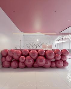 a bunch of pink balloons stacked on top of each other in front of a white wall