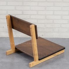 a small wooden chair sitting on top of a cement floor next to a brick wall