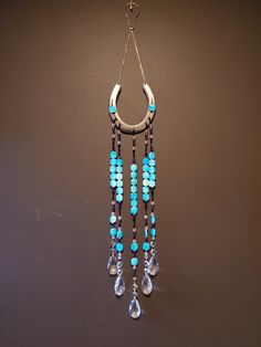 a blue and white necklace hanging from a hook on a brown wall with beads attached to it