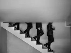 three men in suits climbing up the stairs to their next destination, black and white photograph