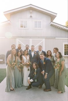 a group of people standing next to each other in front of a white building with a barn