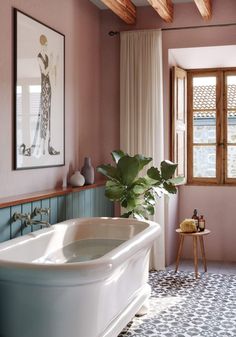 a bath tub sitting next to a window in a room with pink walls and tile flooring