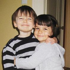 two young children hugging each other in front of a door