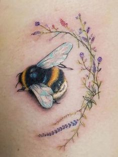 a tattoo with a bee and flowers on the side of her stomach, which is surrounded by leaves