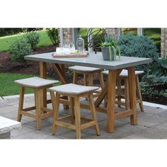 an outdoor table with stools and potted plants