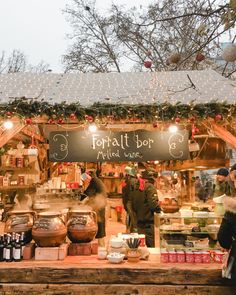 people standing in front of a food stand at an outdoor market with lights on the roof