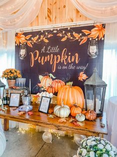 a little pumpkin is on the way sign at a fall themed wedding reception with flowers and candles