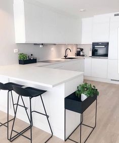 a white kitchen with two stools and a table in front of the counter top