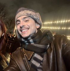 a man and woman standing next to each other in front of a building at night