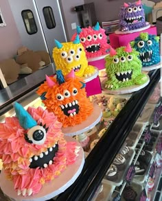 there are many cakes decorated with monster faces on the display case at this store that is filled with cupcakes